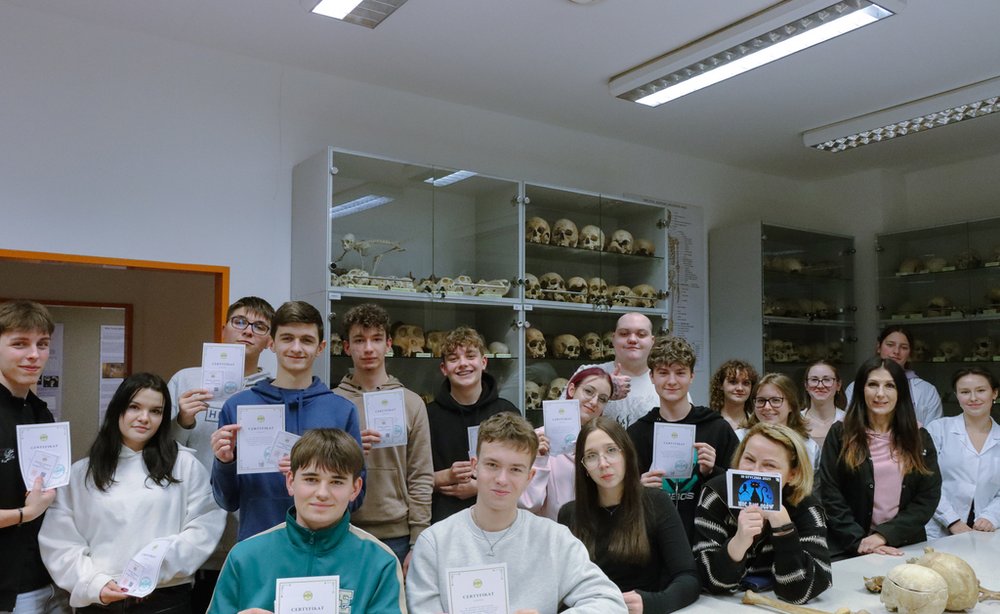 grupa osób trzymająca certyfikaty w pracowni osteologicznej