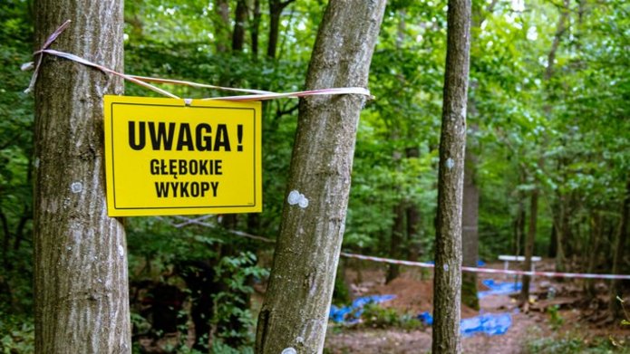 tabliczka z napisem "uwaga głębokie wykopy" rozwieszona na drzewie