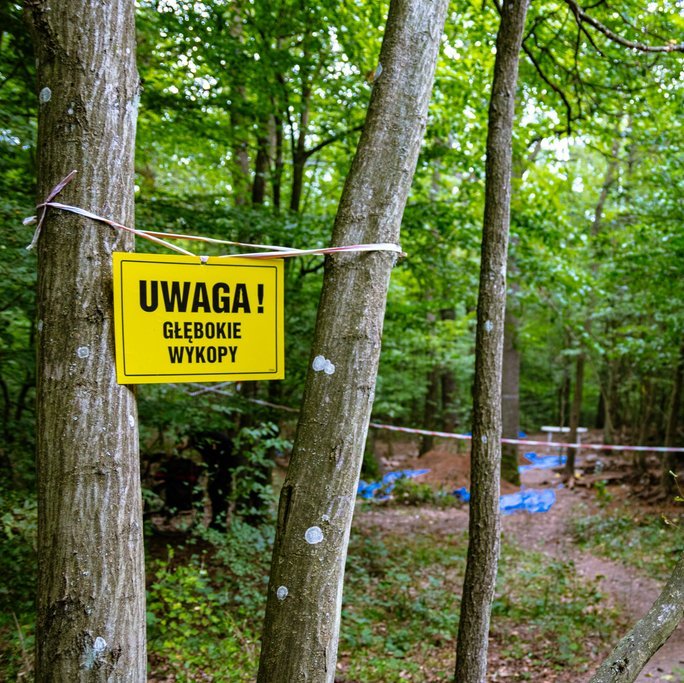 tabliczka z napisem "uwaga głębokie wykopy" rozwieszona na drzewie