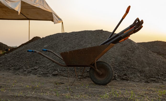 taczka z łopatami na tle hałdy ziemi