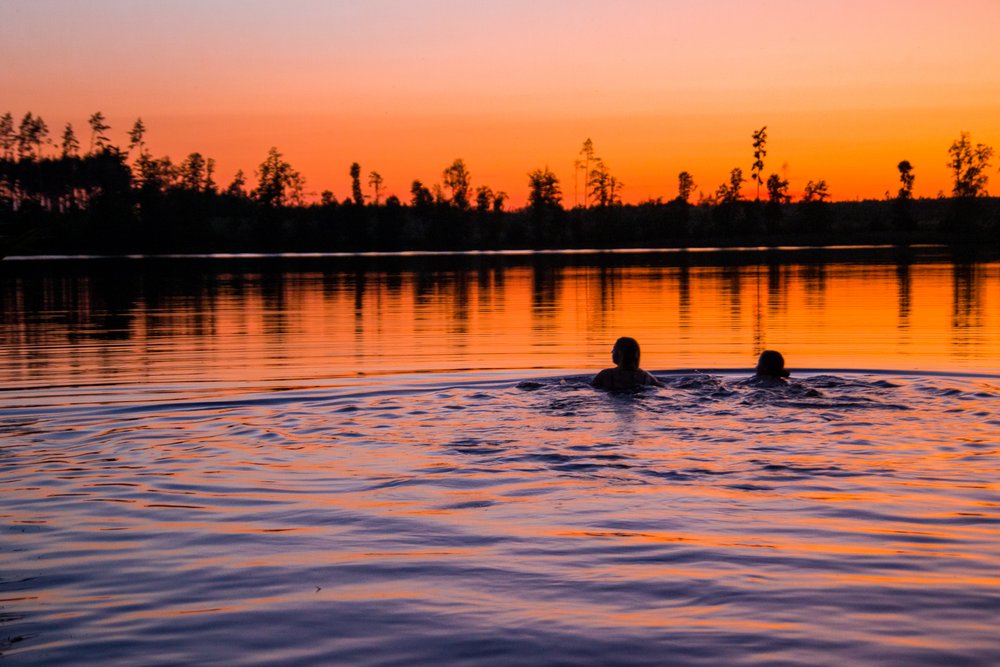 Pływające osoby na tle zachodzącego słońca