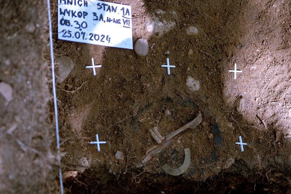 widok odkrytego obiektu archeologicznego z widocznymi metalowymi i ceramicznymi elementami