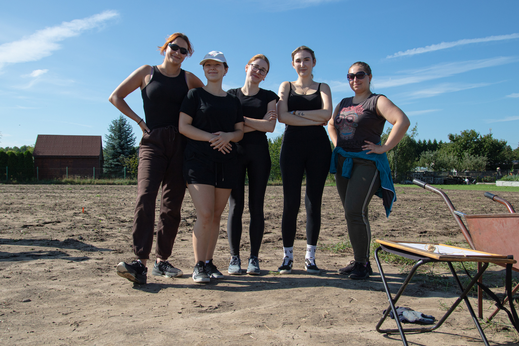 Pięć członkiń Antropołowców pozujących na tle stanowiska archeologicznego
