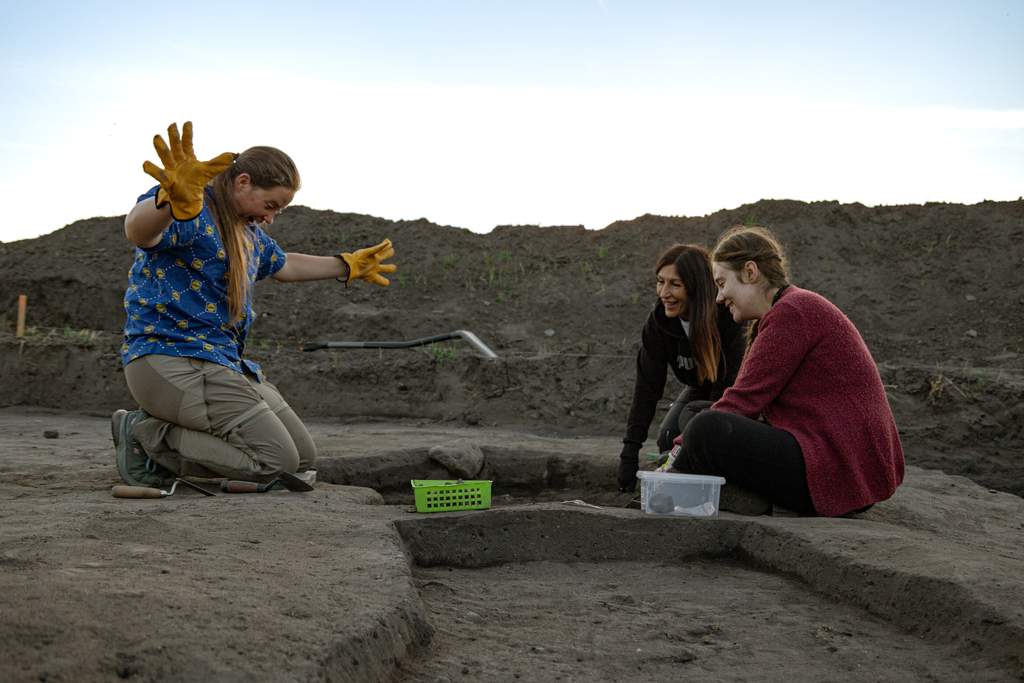 Trzy osoby przy wykopie archeologicznym
