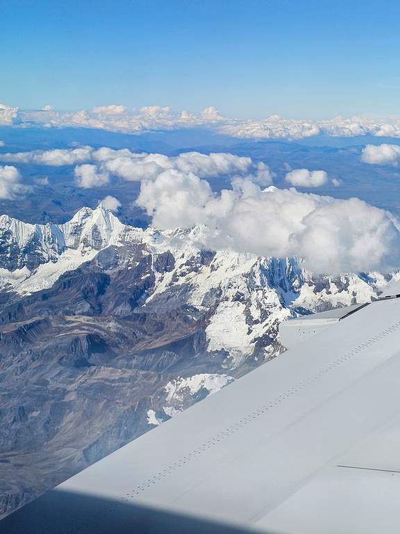 widok z okna samolotu na chmury i góry w oddali